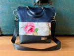 Die Umhängetasche ist Formstabil und dreifarbig. Die Tasche ist aus blauem Canvas und beschichteter Baumwolle weiss im Blumenmuster. Die Tasche ist Wasserabweisend und über dem Kopf zu tragen oder als Rucksack.